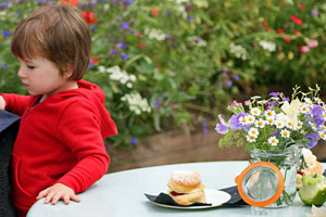 Child eating scones in front of flowers